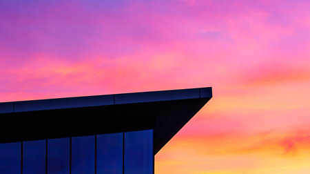 A striking image showcasing modern architecture with a bold silhouette against a stunning sunset sky. The vibrant hues blend seamlessly, creating a captivating scene.の素材