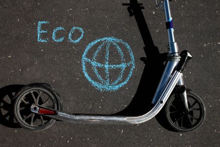 Kick scooter lying on grey asphalt with drowings eco and planet Earthの写真素材