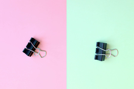 Black metal paper clip on pink and mint green double Phono background