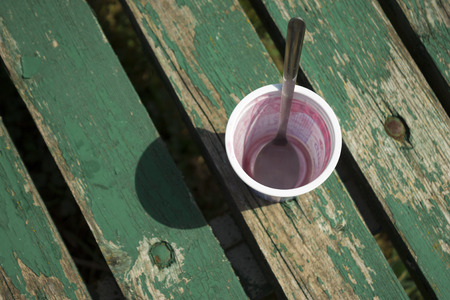 Empty ice cream Cup with metal spoon inside on green wooden background with cracked paintの写真素材