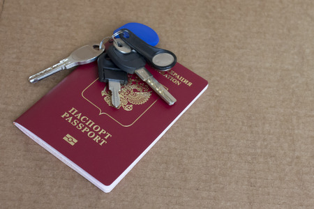 Bunch of keys and the international passport of the Russian Federation on a brown background with...