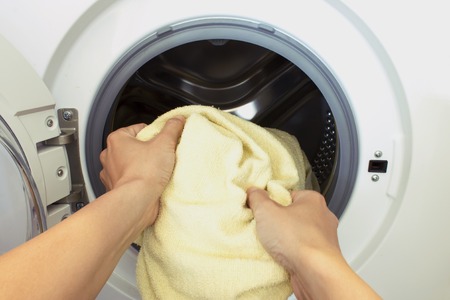 Womans hands pull the laundry out of or load the washing machineの写真素材