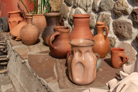 Many ceramic handmade utensils on stone shelf outdoor