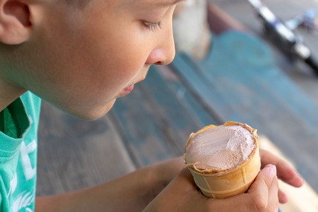 A boy sitting on wooden stairs and eating icecreamの写真素材