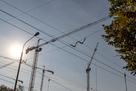 Industrial landscape with silhouettes of cranes and power lines, city construction concept.の写真素材