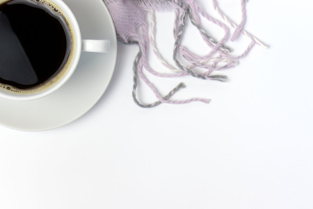 White ceramic cup of coffee and pink knitted plaid on white with copy space.