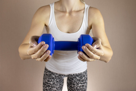 Cropped woman in white shirt with dambbell in her hands clase up. Slimming diet and fitness concept.の写真素材