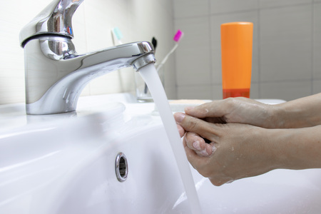 Hygiene concept. Washing hands with soap under the faucet with water.