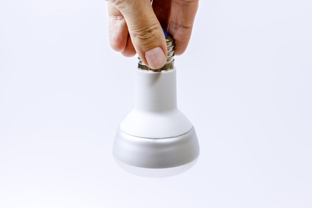 A hand holding an energy saving lamp on white background.の写真素材