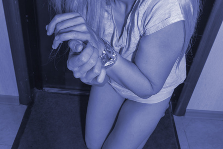 Frightened woman sitting on the floor at night, domestic violence and crime concept.