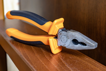 Pliers with orange handles on brown wooden plank.の写真素材