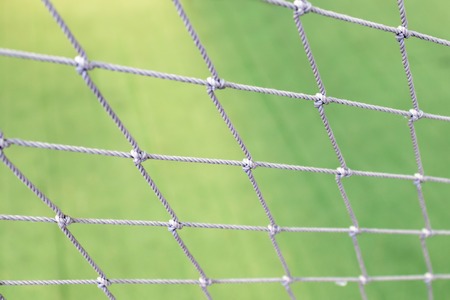 Football net close up on green grass football field background.