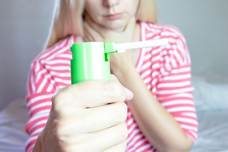 Spray for sore throat. Photo of a woman who holds spray in her hand. The concept of health and disease.の写真素材