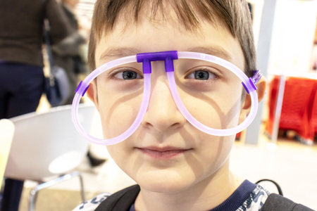 Portrait of funny cute boy wearing strange glasses made of fluorescent neon tubes, shopping mall.の写真素材