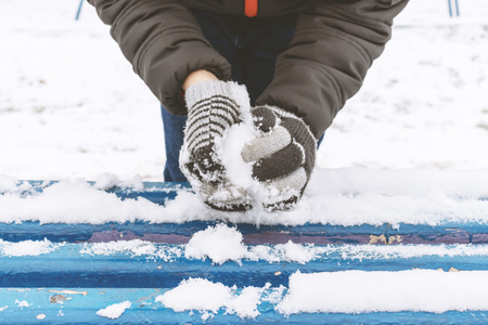 Boy's hands wearing mittens, gloves sculpts snowballs, outdoor winter activities, sports concept.の写真素材