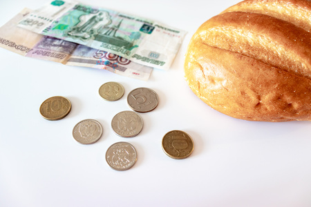 A piece of white bread, coins and paper rubles on the table. The concept of poverty, lack of money...