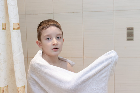 A preteen boy drying his hair with white towel - children, kid independence concept.の写真素材