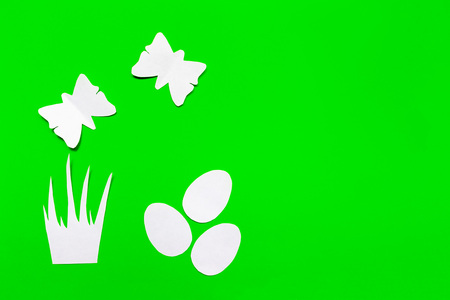 Three white easter eggs, grass and butterflies cut of paper on green background, easter and spring...
