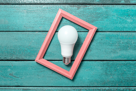 LED energy saving bulb in wooden frame on green vintage background with peeling paint.の写真素材