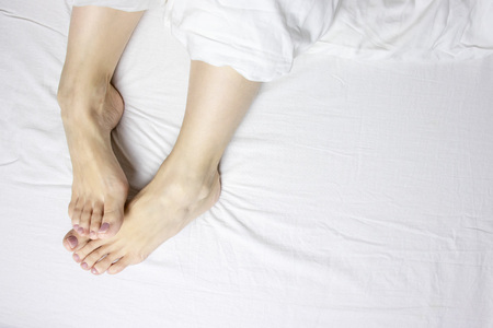 Woman legs, bare feet awaking in the morning from sleep and relaxing, copy space.