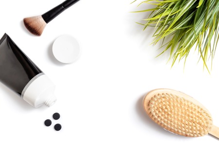 Charcoal facial mask and scrub in tube with a wooden body brush, scrubbing and skincare concept,...