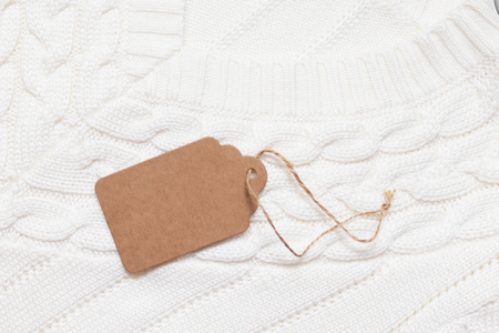 Brown cardboard label, tag with slim rope cord on white knitted background.の写真素材