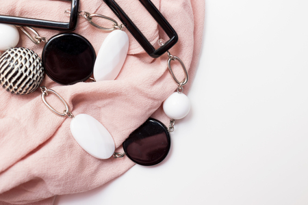 Black and white bijouterie necklace with geometric beads and beige luxury fabric on white background with copy space.の写真素材