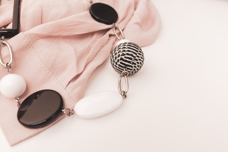 Black and white bijouterie necklace with geometric beads and beige luxury fabric on white background...