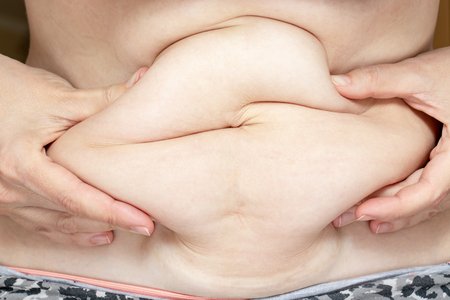 Woman holding her fat eblly, stomach with hands, diet, weight loss and liposuction concept.の写真素材