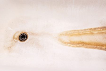 Extremely dirty bath drain mesh, hole and surface covered with limescale or lime scale and rust, cleaning calcified and rusty bathroom equipment conceptの写真素材