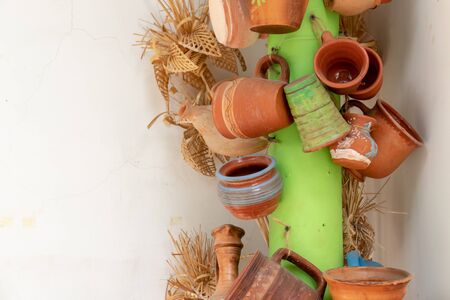 Many ceramic handmade utensils made of clay, hanging on a green column, close up with copy space.の写真素材
