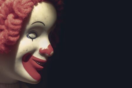 Scary evil sinister clown face with a spooky smile on black background with copy space, coulrophobia and fears concept.の写真素材