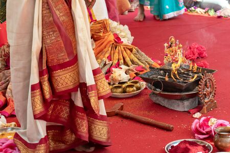Indian wedding ceremony, decorations for traditional ethnic rituals for marriage, fire burning, flowers and statuettes of the deity on red carpet.の写真素材