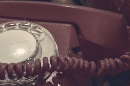 Old vintage red rotary dial phone close up toned sinister creepy colors, halloween and horror concept.の写真素材