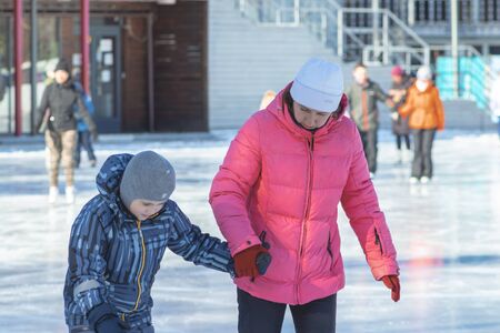 MOSCOW, RUSSIA- MARCH 02, 2019: Woman teaching her child to skate on a winter skating rink, family leisure and sport activity on christmas vacations and holidays.のeditorial素材
