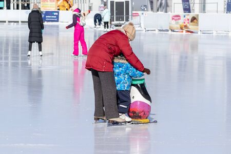 MOSCOW, RUSSIA- MARCH 02, 2019: Woman teaching her child to skate on a winter skating rink, family leisure and sport activity on christmas vacations and holidays.のeditorial素材