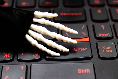 Skeleton hand ready to work on computer, laptop gaming keyboard.