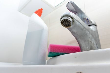 Cleaning products, agents and sponge for washing dirty faucet with limescale, calcified water tap with lime scale on washbowl in bathroom.の写真素材