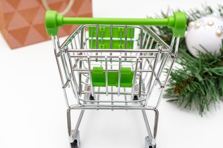 Empty shopping cart, trolley on white background with craft paper shopping bag and green decorated fir tree branches.の写真素材