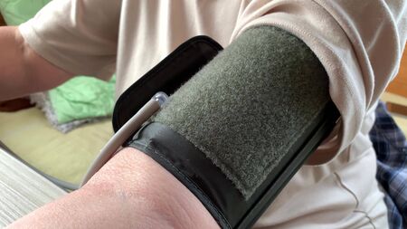 Hand of an elderly senior woman with hypertension measuring blood pressure with automatic tonometer at home.の写真素材