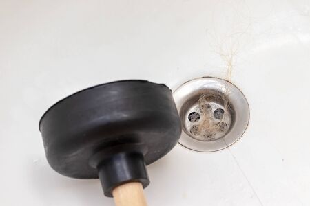 Blocked sewer, clogged bath drain with fallen out hair and a plunger near, hair loss in a bathroomの写真素材