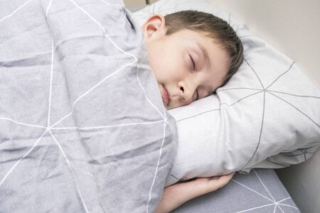 A preteen kid boy sleeping in bed at home, bedtime and sweet dreams concept.の写真素材