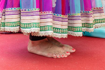 Female feet in a sari standing on a red carpet during wedding ceremony.の写真素材