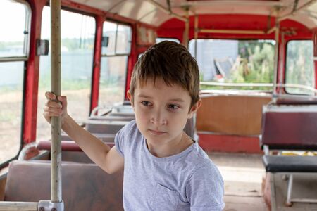 A 10 years boy riding in a old vintage bus, he is sad because his poor life and the bus moving going...