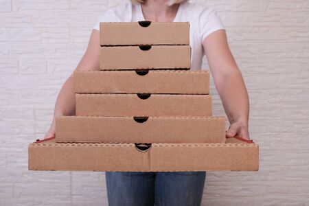 Woman holding many pizza boxes of different sizes.の写真素材