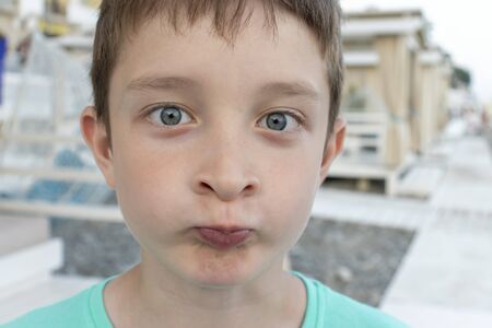 Failed summer vacation concept, a portrait of despared, upset boy with funny face on a beach, sea...