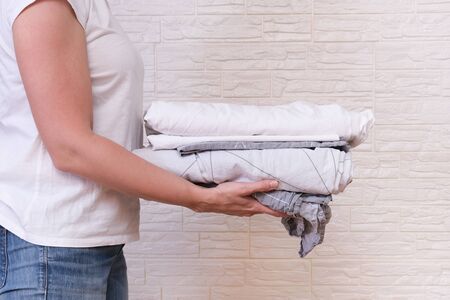 Woman housewife holding a stack of washed folded bed linen. washing clothes and linen, housekeeping...