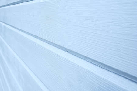 A blue painted wooden wall of a frame country house, blue wooden background, planks close up, copy...