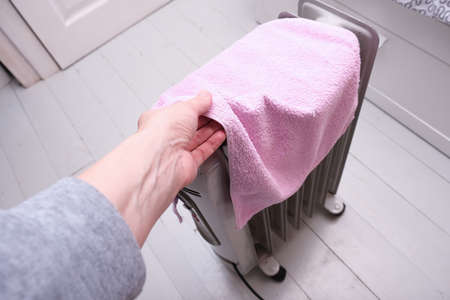 A dangerous hazardous situation with mobile oil heater covered with a towel, that is dryin on a hot electrical device, appliance, do not cover risk of fireの写真素材