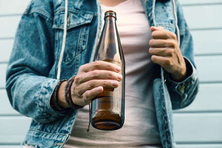 A drunked woman dressed punk, informal drinking beer from a brown bottle, alcohol overdosage and...